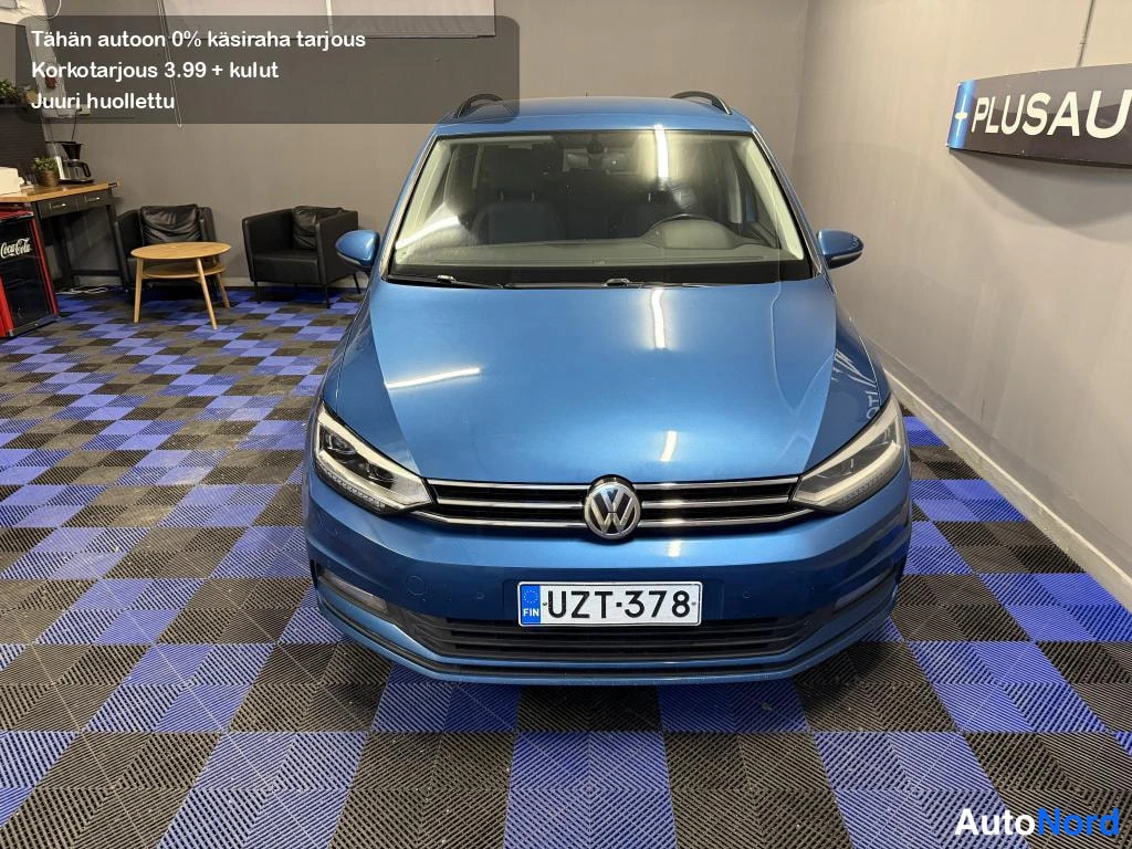 Edestä: Sinisen Volkswagen Touran -henkilöauton etunäkymä suoraan edestä, rekisterikilpi.
