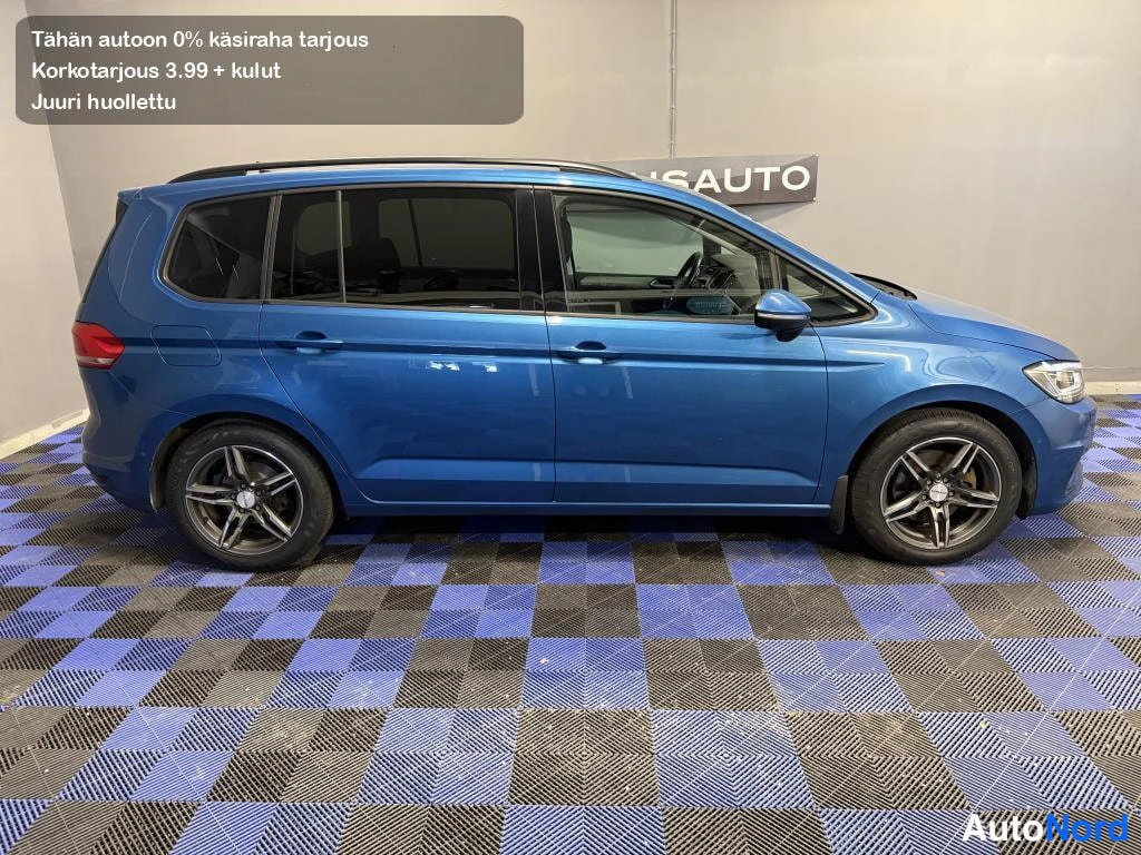 Sivulta: Sininen Volkswagen Touran -henkilöauto sivulta kuvattuna, vasen sivu näkyvissä sisätiloissa.