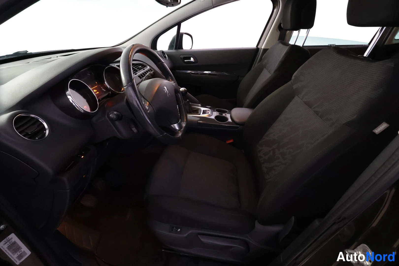 Muu: Kuljettajan istuimelta kuvattu näkymä Peugeot 3008:n etumatkastamoon, tummat kankaiset istuimet ja ohjauspyörä.