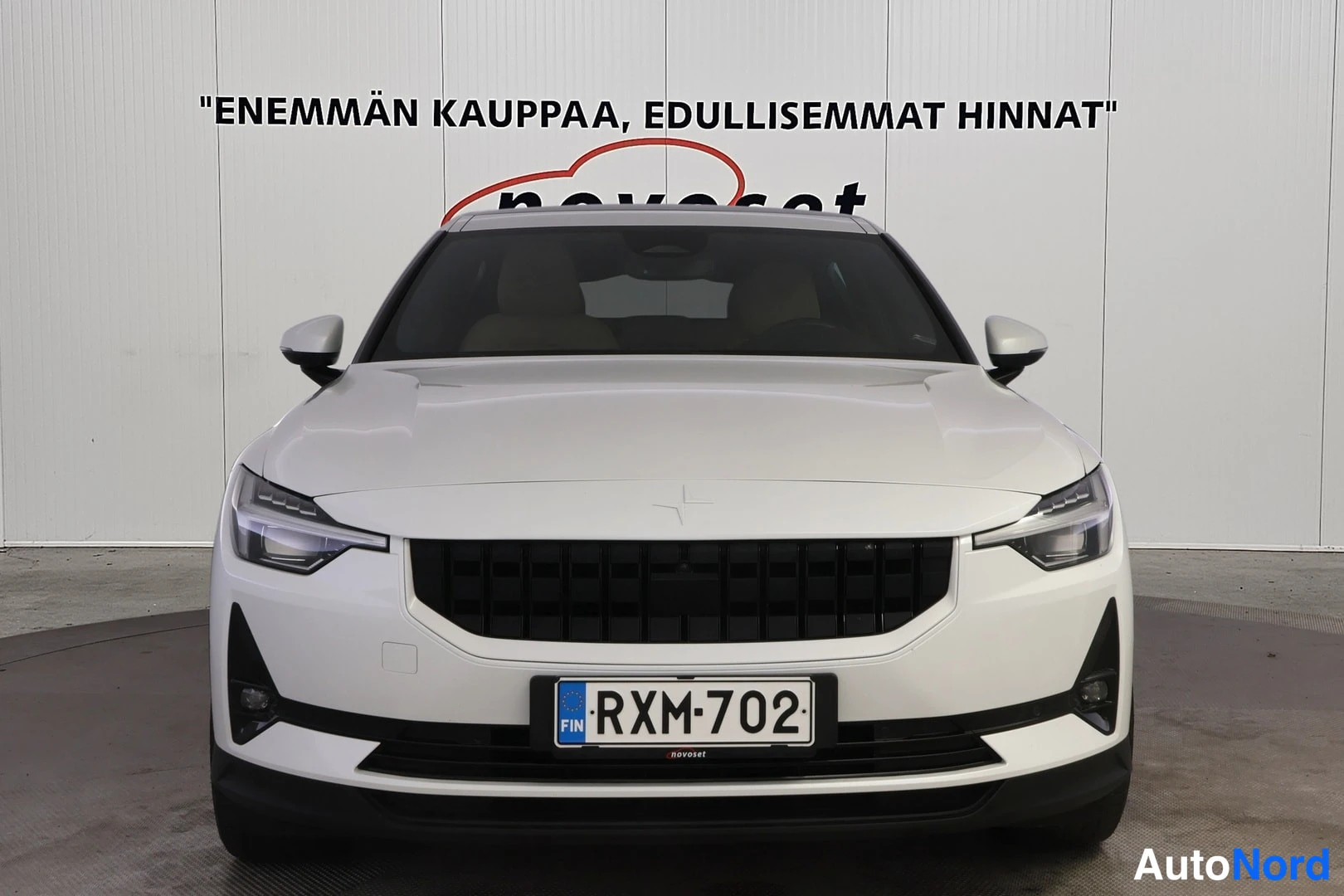 Edestä: Valkoisen Polestar 2:n etunäkymä, musta etusäleikkö ja rekisteritunnus RXM 702.
