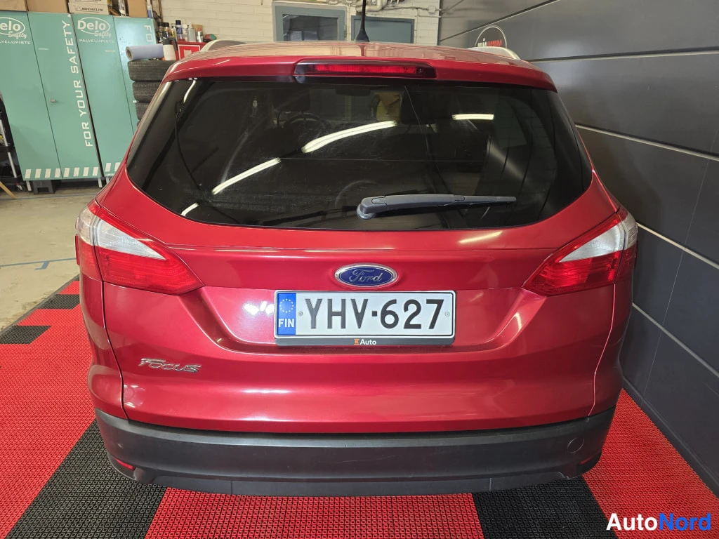 Takaa: Punaisen Ford Focus -farmarin takaosa suoraan takaa: takaluukku, Ford-merkki, Focus-teksti, takavalot ja rekisterikilpi.