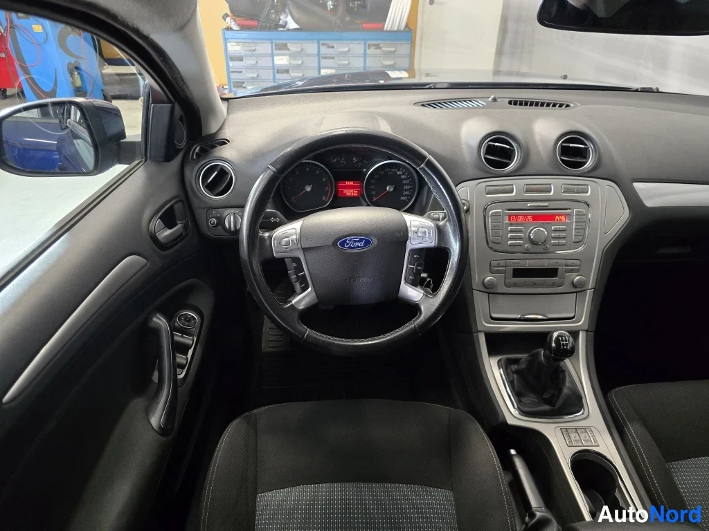 Muu: Ford Mondeo kojelauta ja ohjauspyörä; radio näyttää kelloa 01:06, taajuus 94.6.