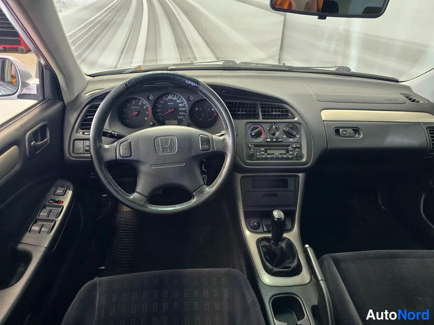 Muu: Honda Accordin kojelauta ohjaamosta: Honda-ohjauspyörä, analogiset mittarit, radio ja manuaalivaihteen keksi.