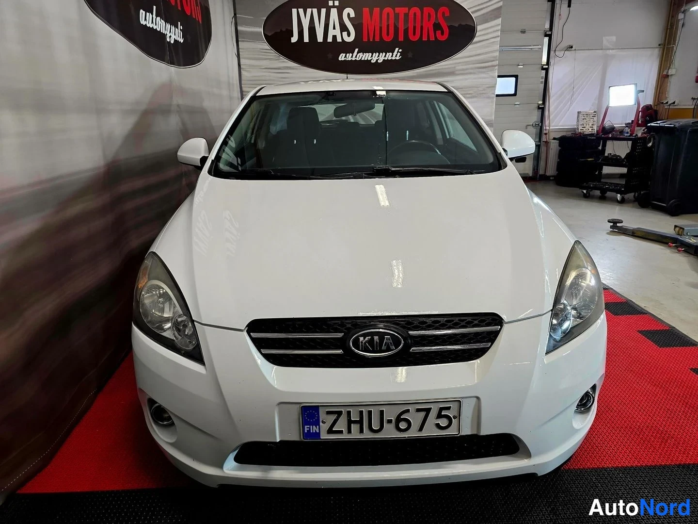 Edestä: Kia ProCeedin etupuoli valo­studiossa: valkoinen kori, KIA-merkki etusäleikössä ja EU-rekisterikilpi.