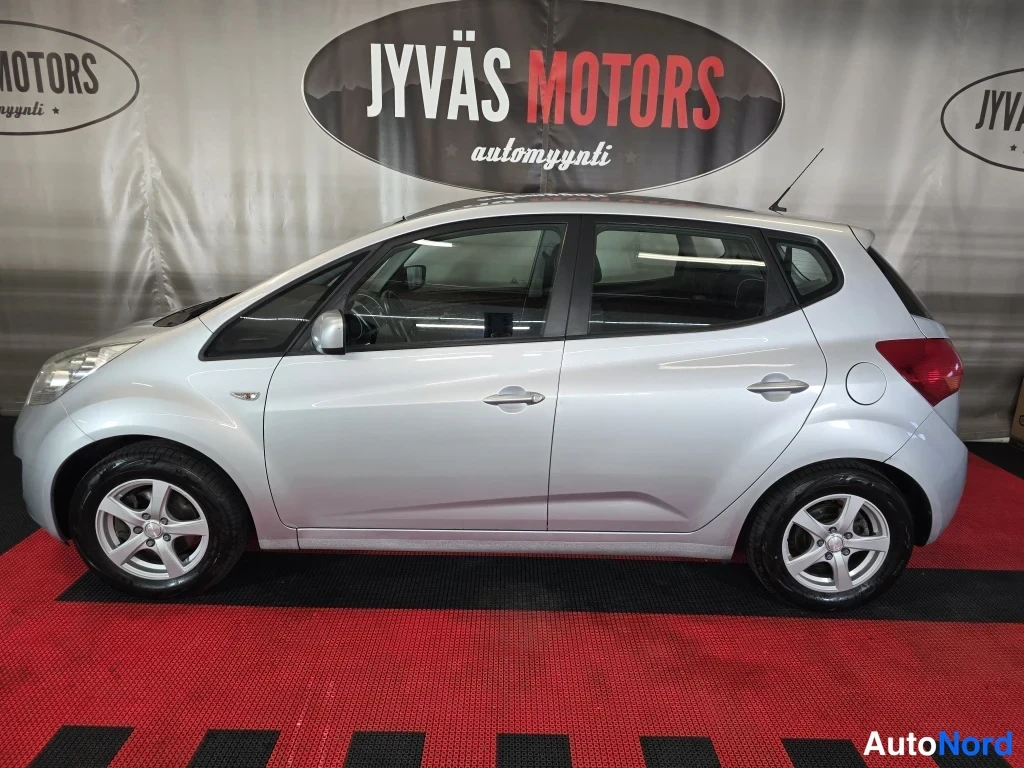 Sivulta: Hopeanvärinen Kia Venga -henkilöauto sivulta kuvattuna autonmyyntitilassa.