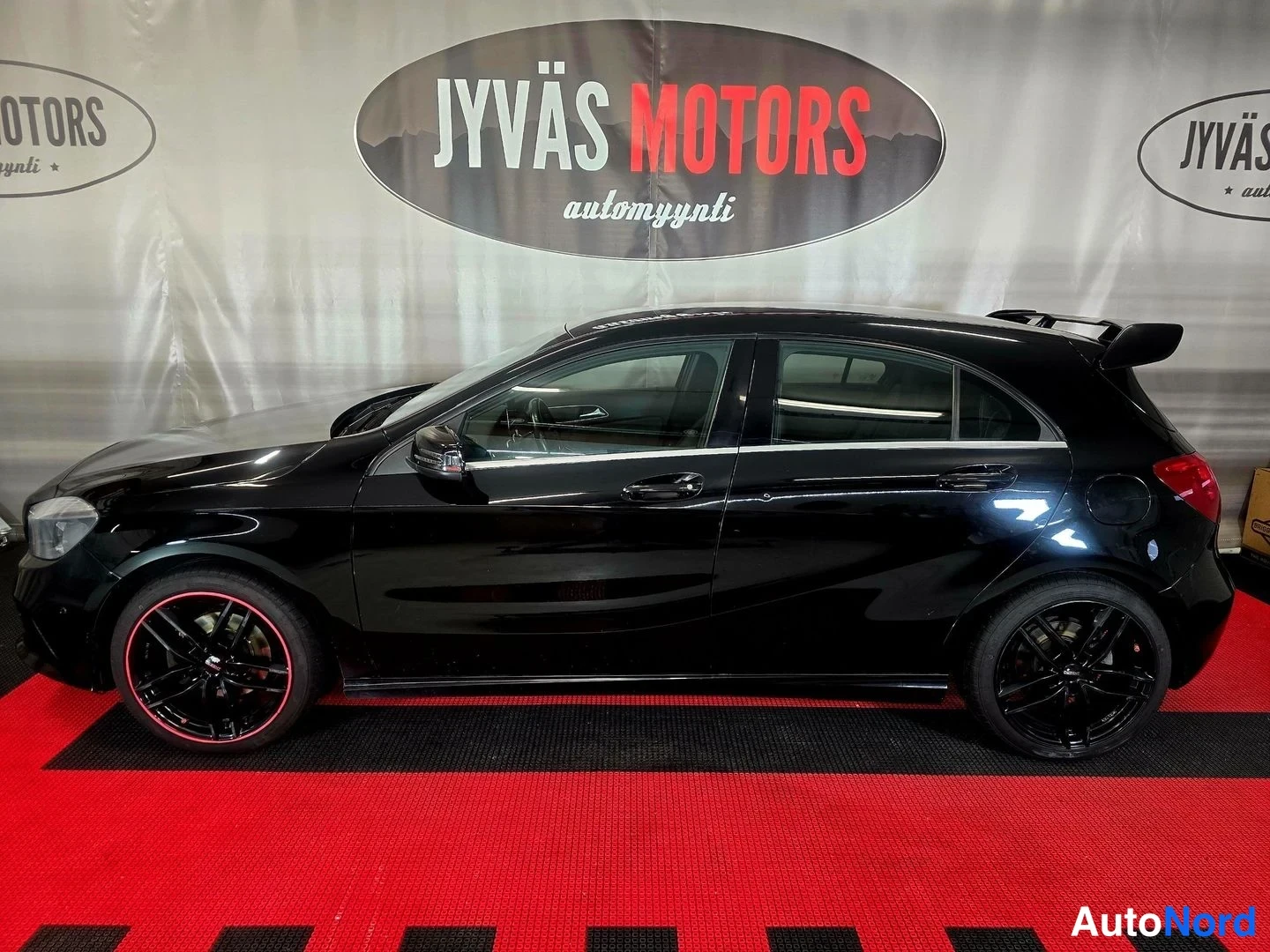 Sivulta: Musta Mercedes-Benz A-osa hatchback sivulta kuvattuna, tummat vanteet ja takavalo osittain näkyvissä.