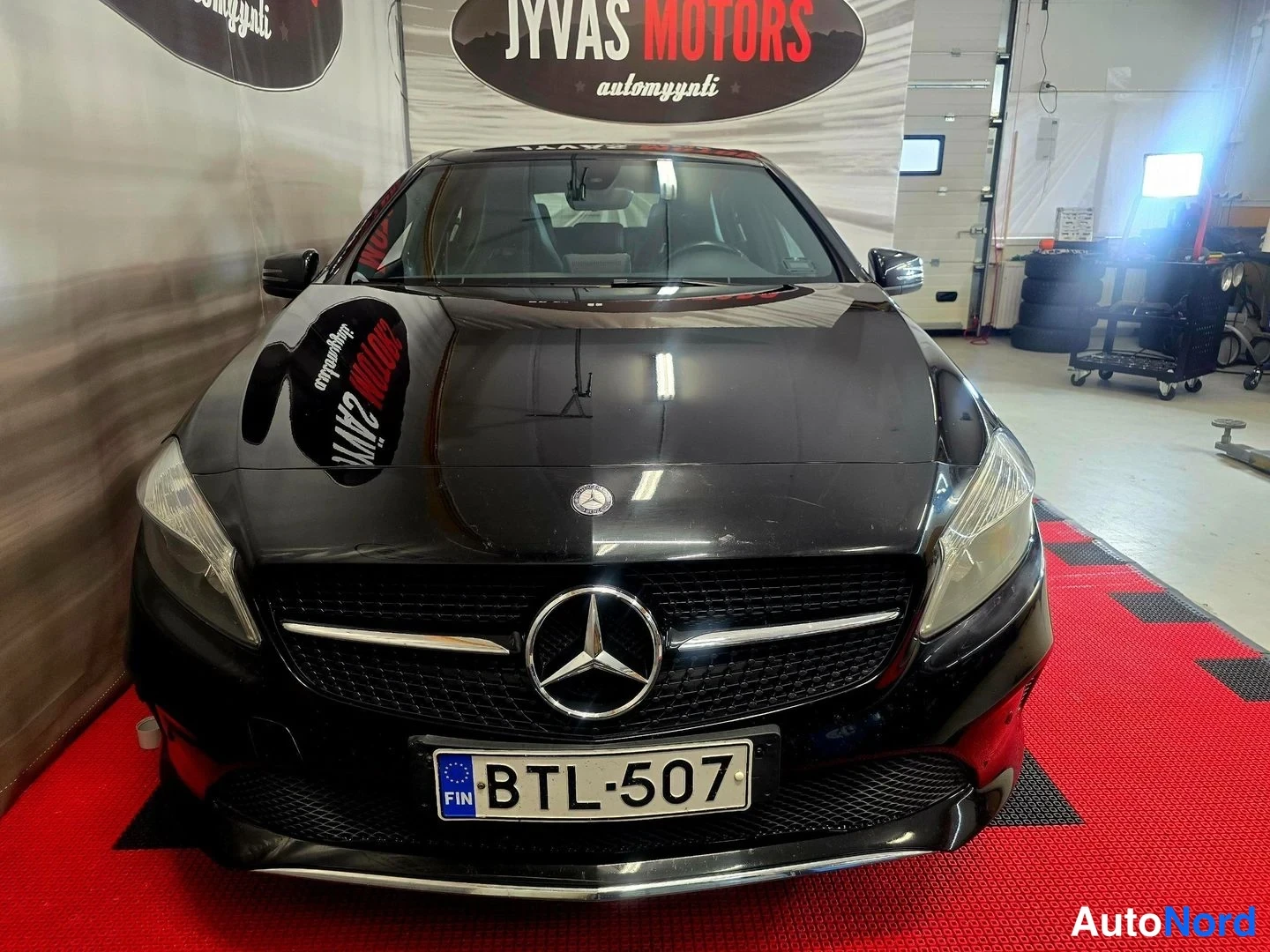 Edestä: Musta Mercedes-Benz A-osa edestä päin kuvattuna, rekisterikilpi näkyvissä.