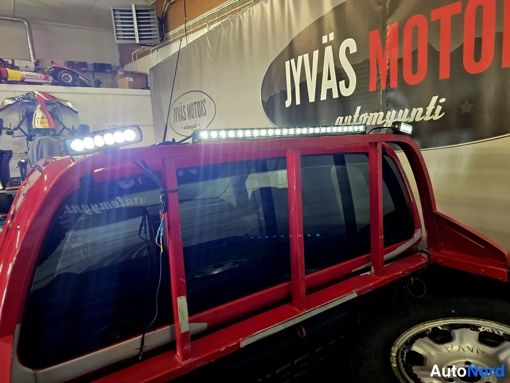 Takaa: Punaisen lava-auton lavan yläpuolella kattoteline ja kaksi LED-valopalkkia.
