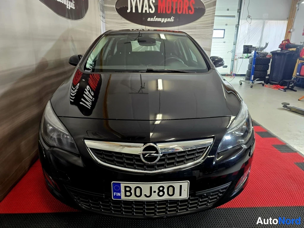 Edestä: Mustan henkilöauton etupää suoraan edestä kuvattuna; Opel-merkki keulassa ja rekisterikilpi B0J-801.