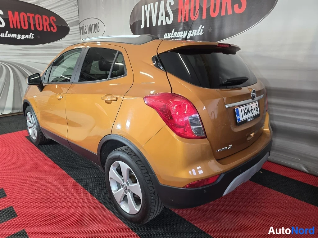 Takaviisto: Oranssi Opel Mokka X takakulmasta, takavalot ja rekisterikilpi näkyvät.