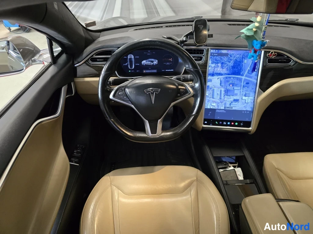 Muu: Kuljettajan puolen sisänäkymä: Tesla-ohjauspyörä, digitaalinen mittaristo ja keskikonsolin suuri kosketusnäyttö, beigea nahkapintaa.