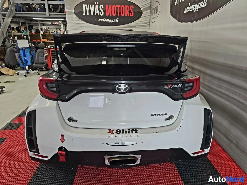 Takaa: Toyota Yaris -ralliauto suoraan takaa, valkoinen korimusta hiilivirtahepo ja GR-Four-merkintä.
