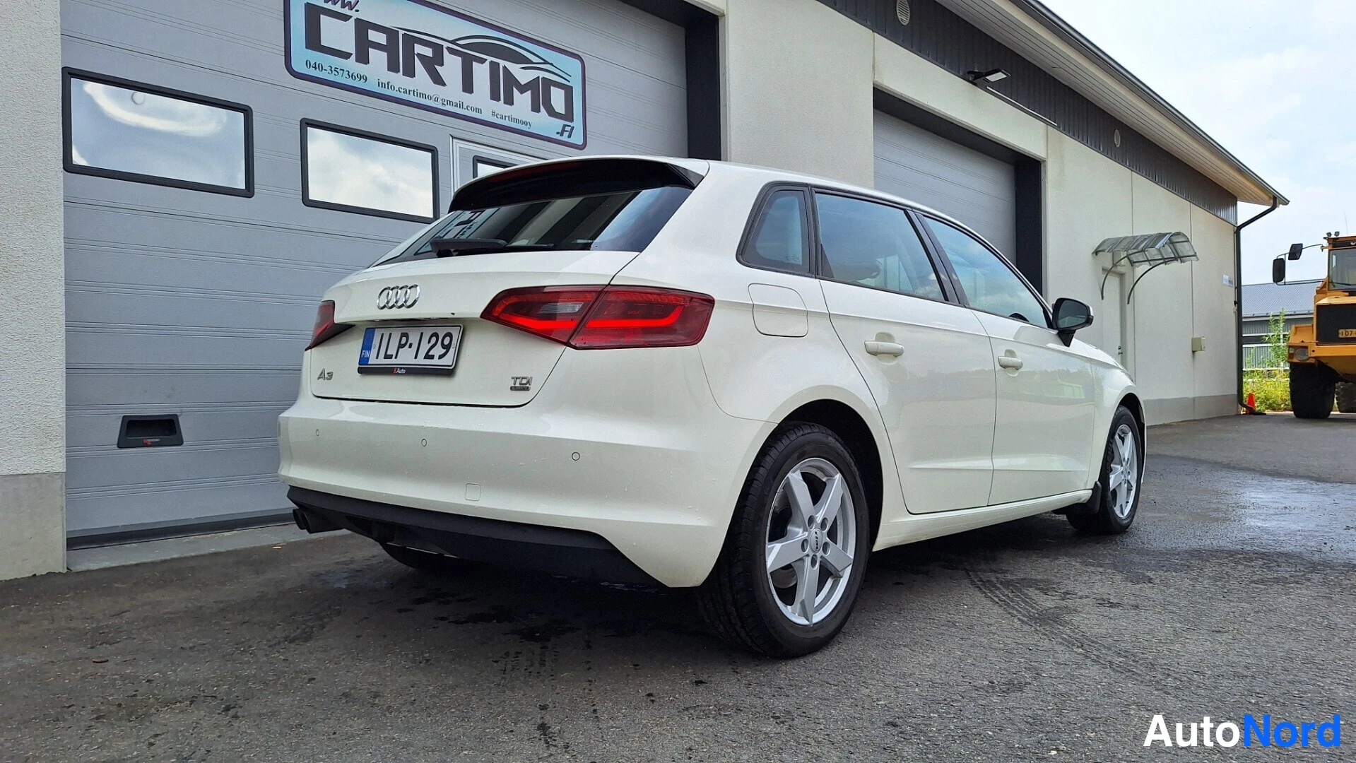 Takaviisto: Valkoinen Audi A3 -viistoperä takaviistosta kuvattuna kiinteistön pihalla.