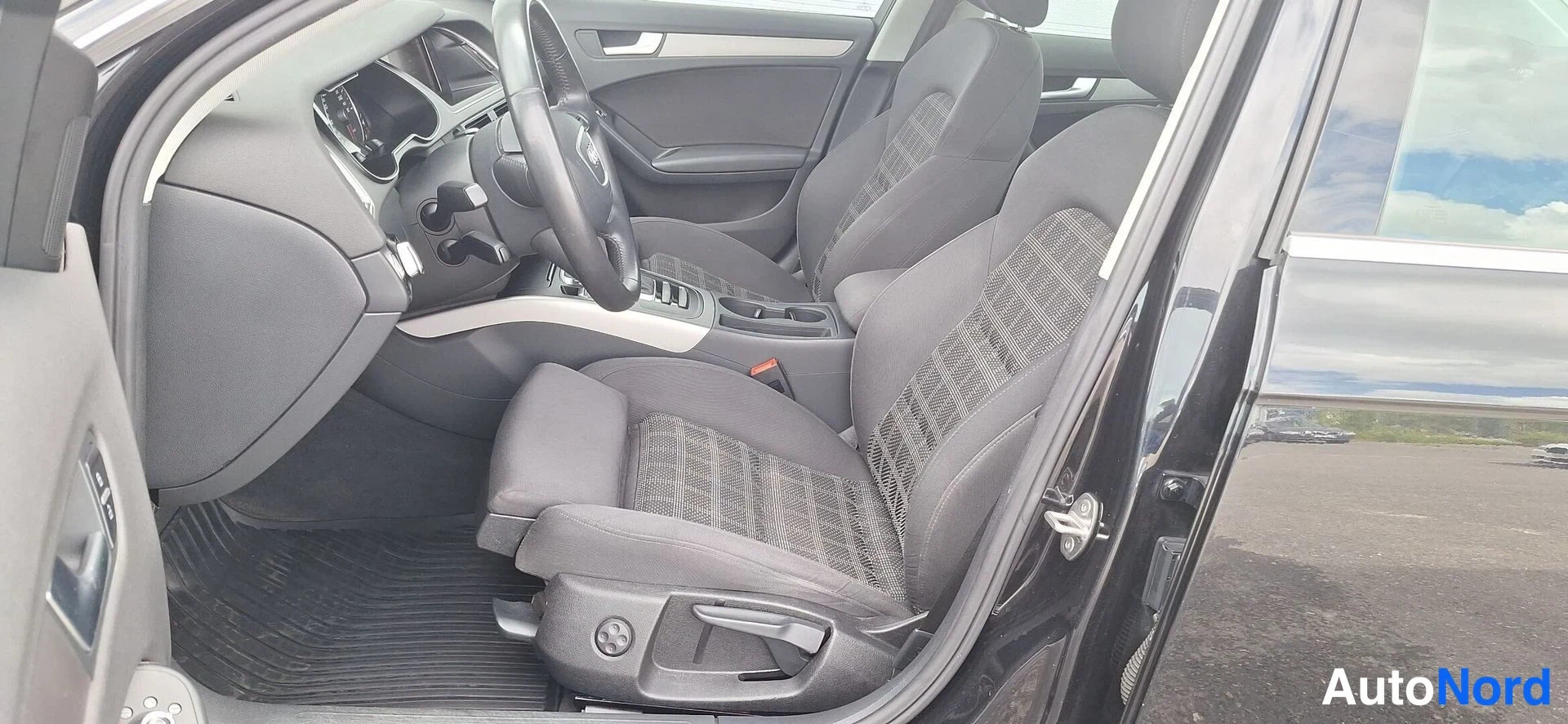 Muu: Audi-nelopyörän etuistuimet ja keskikonsoli kuvattu avoimen ovikotelon läpi.