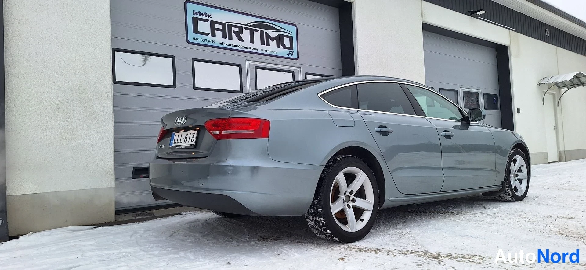 Takaviisto: Audi A5 Sportbackin takakulma ja oikea kylki lumisella pihalla