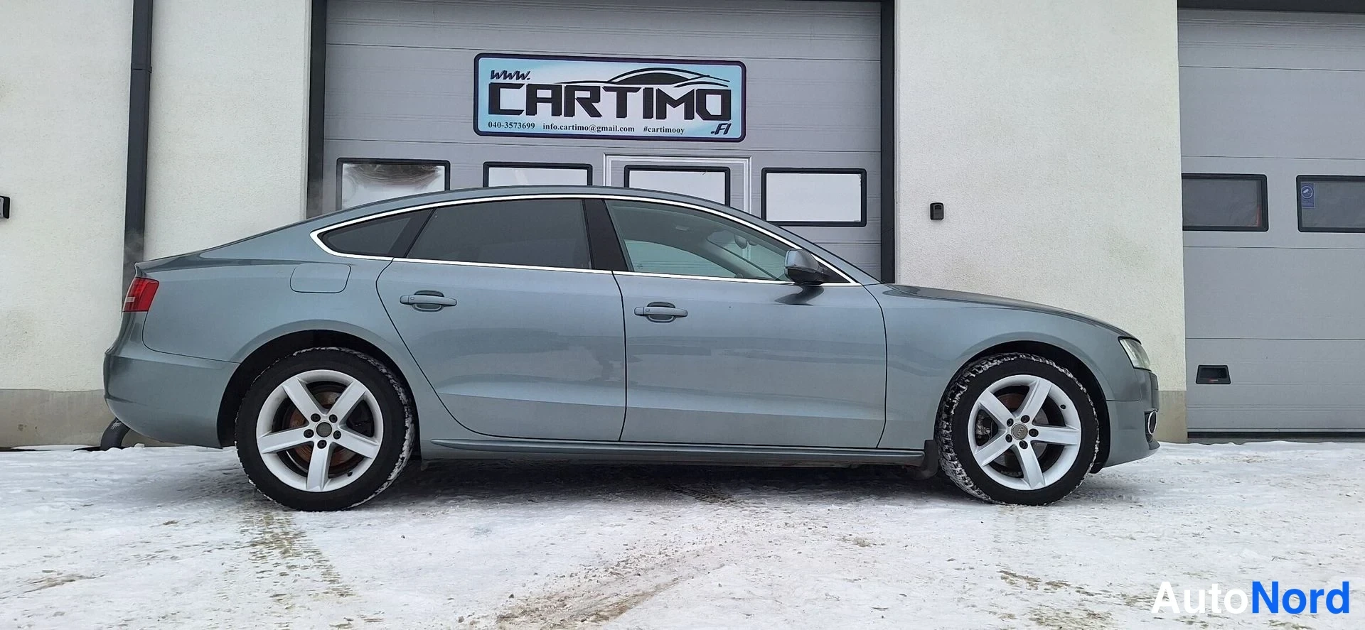 Etuviisto, nokka oikealle: Audi A5 Sportbackin kylki ja etunosan reuna, auton keula osoittaa kuvan oikeaan reunaan.