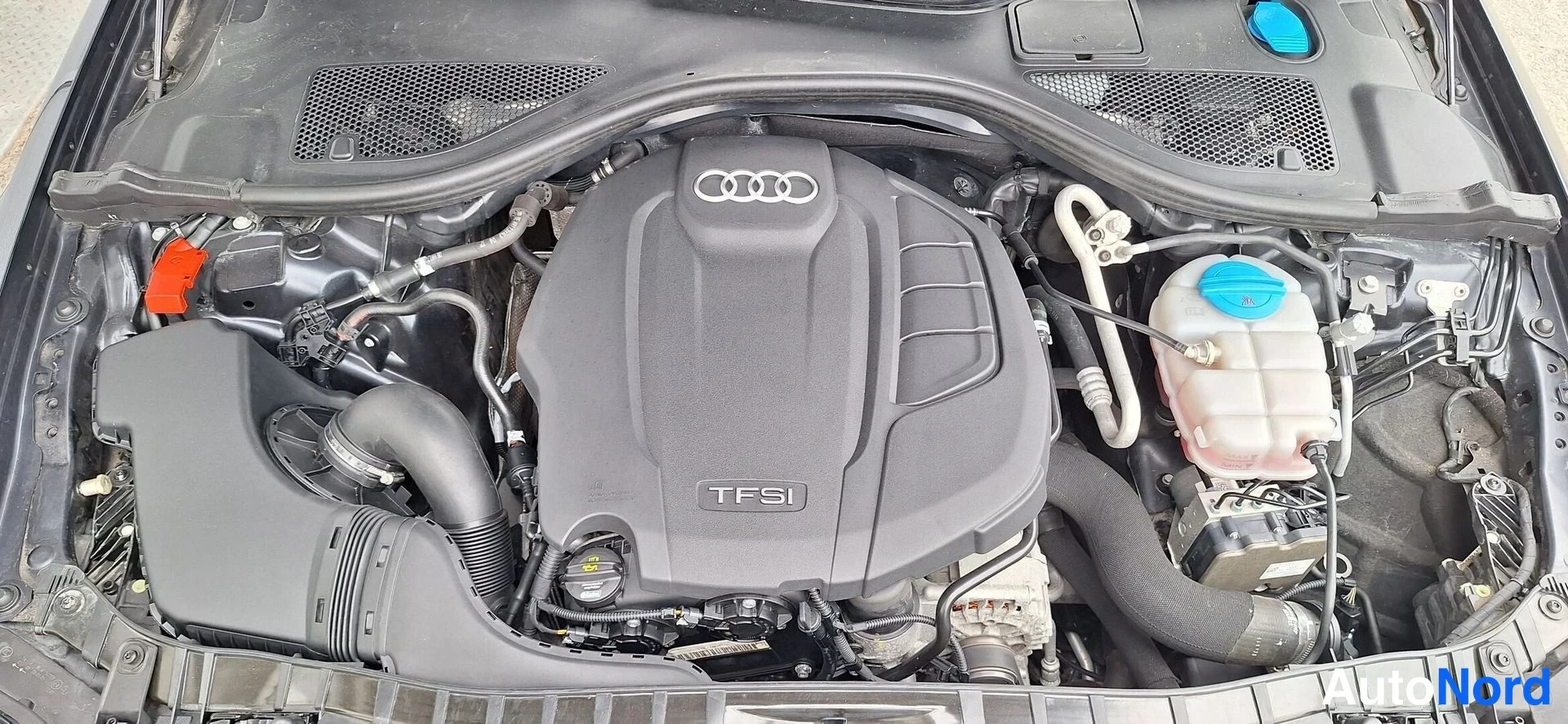 Edestä: Audi A6:n moottoritila, TFSI-merkitty moottorin kansi näkyvissä.