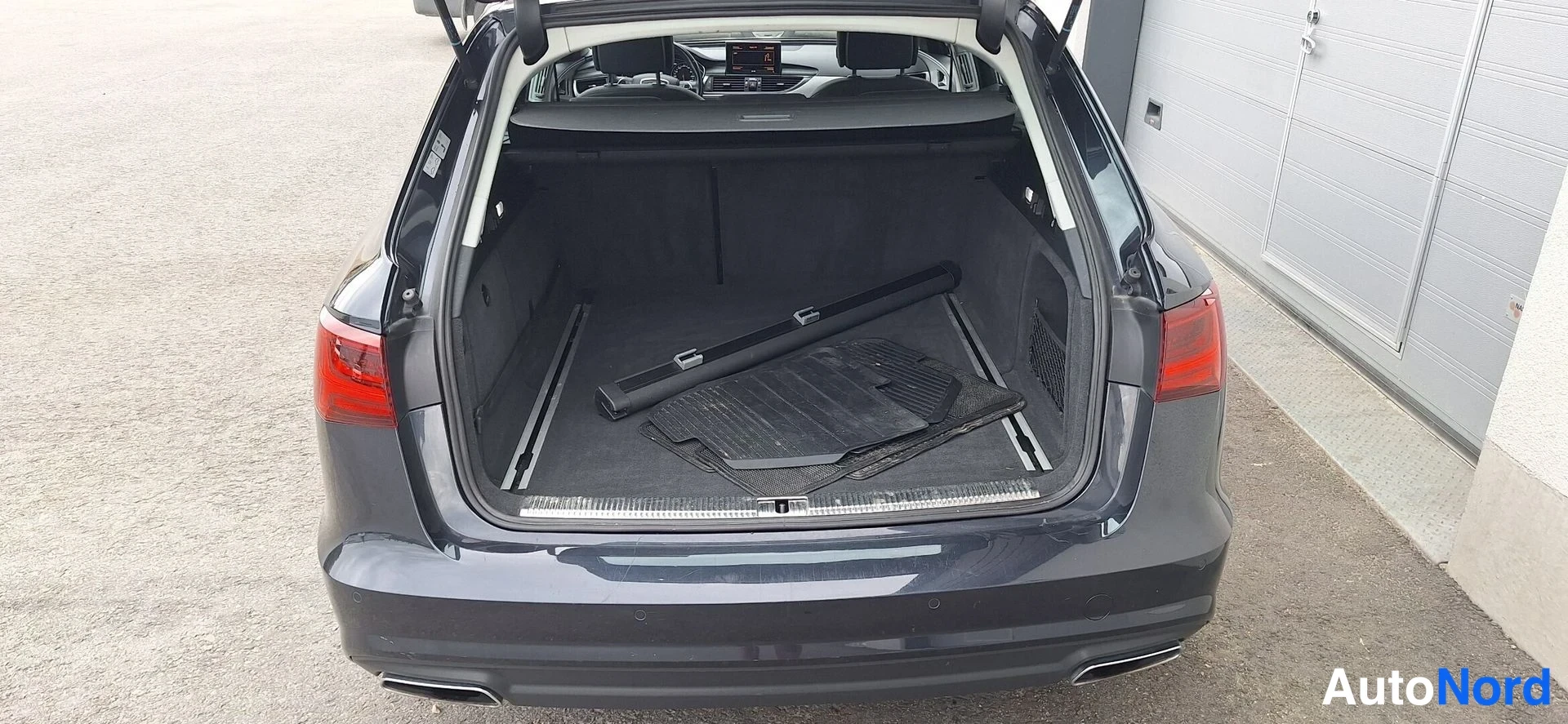 Takaa: Audi A6 Avantin auki avattu tavaratila, tummansininen koriväri.