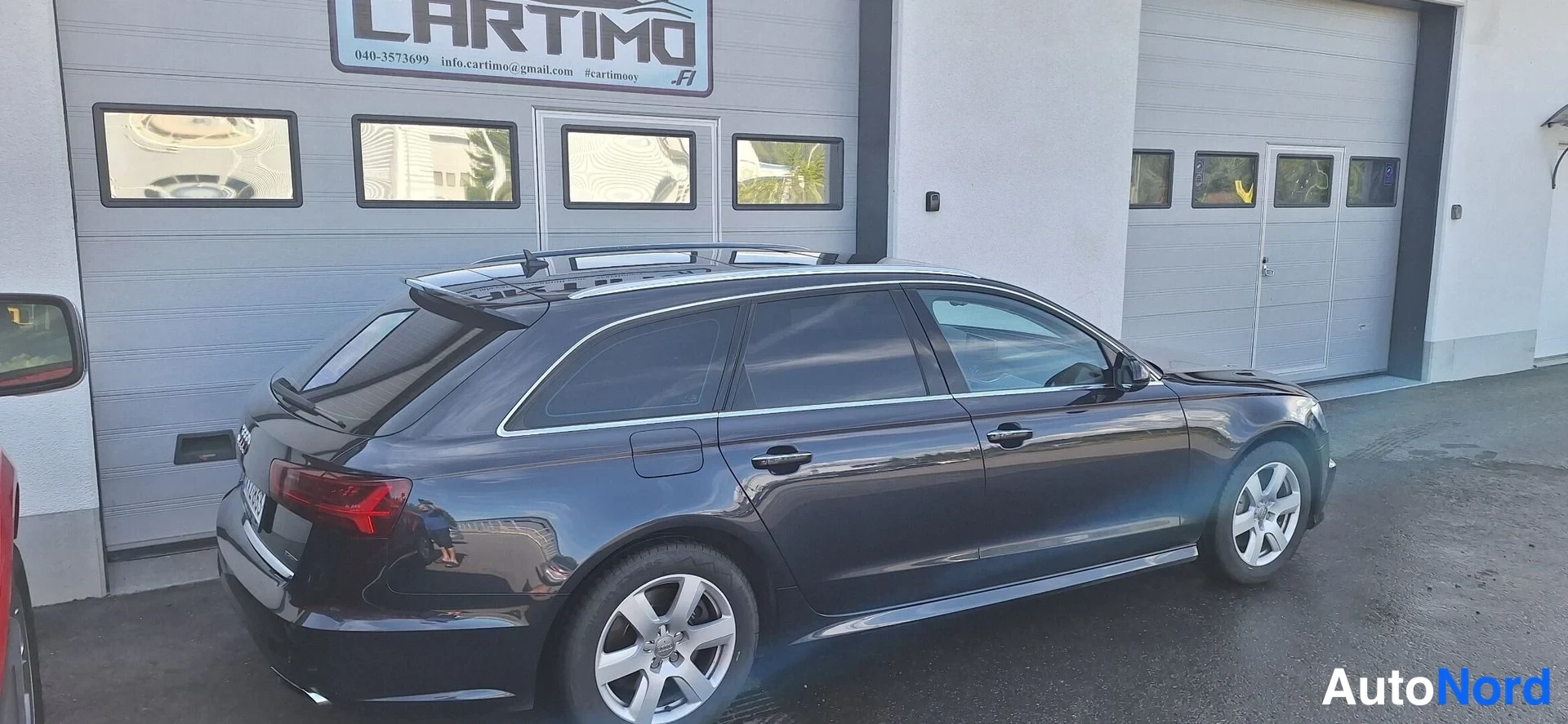 Takaviisto: Audi A6 -farmari takaa viistosti vasemmalta, kattokaiteet