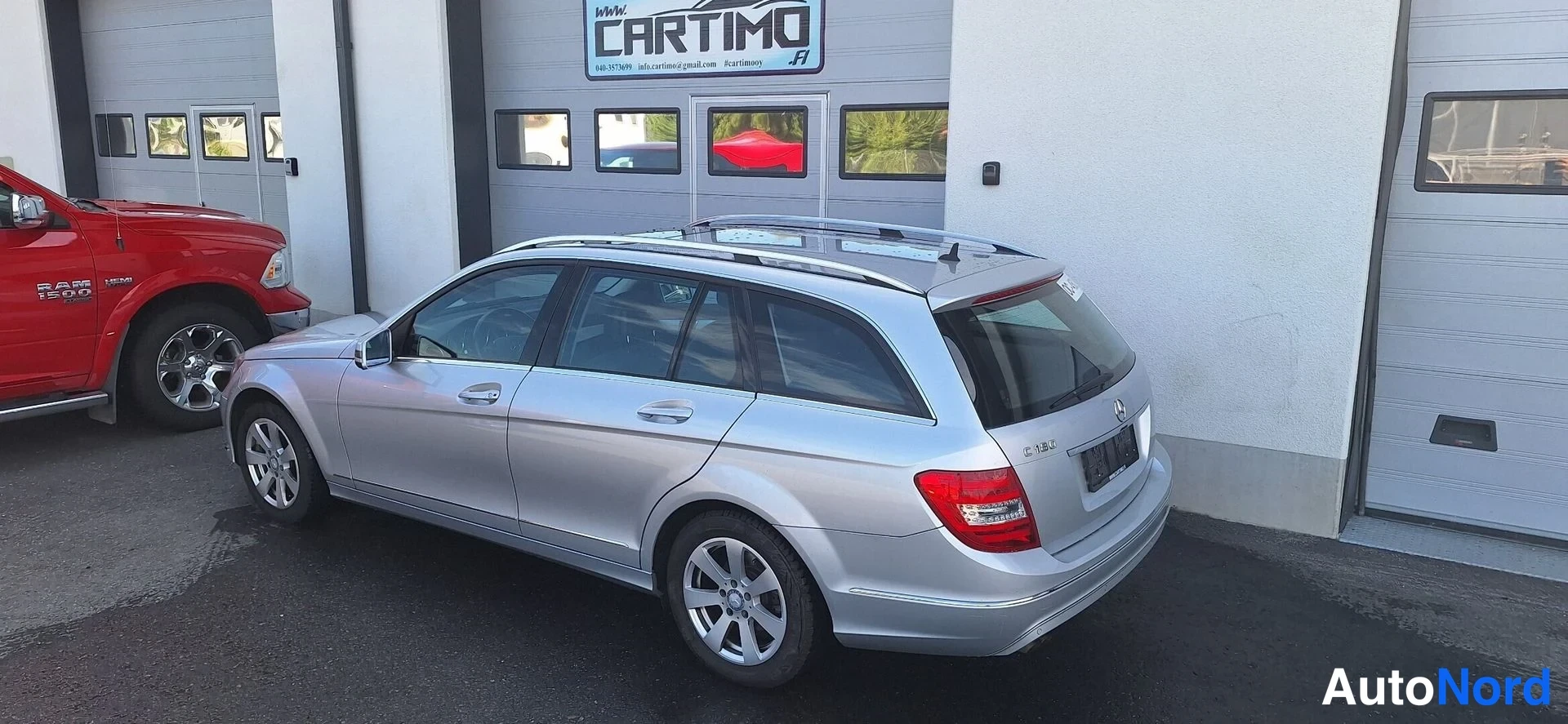 Takaviisto: Hopeanvärinen Mercedes-Benz C -farmari takapuolelta ja vasemmalta sivulta, takavalot ja avattavan luukun alue näkyvät.