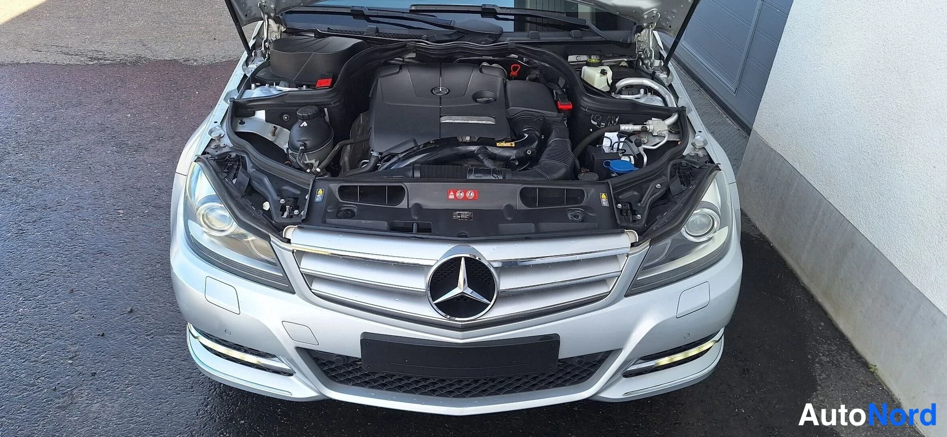 Edestä: Hopeaisen Mercedes-Benzin avoin moottoritila kuvattuna edestä.
