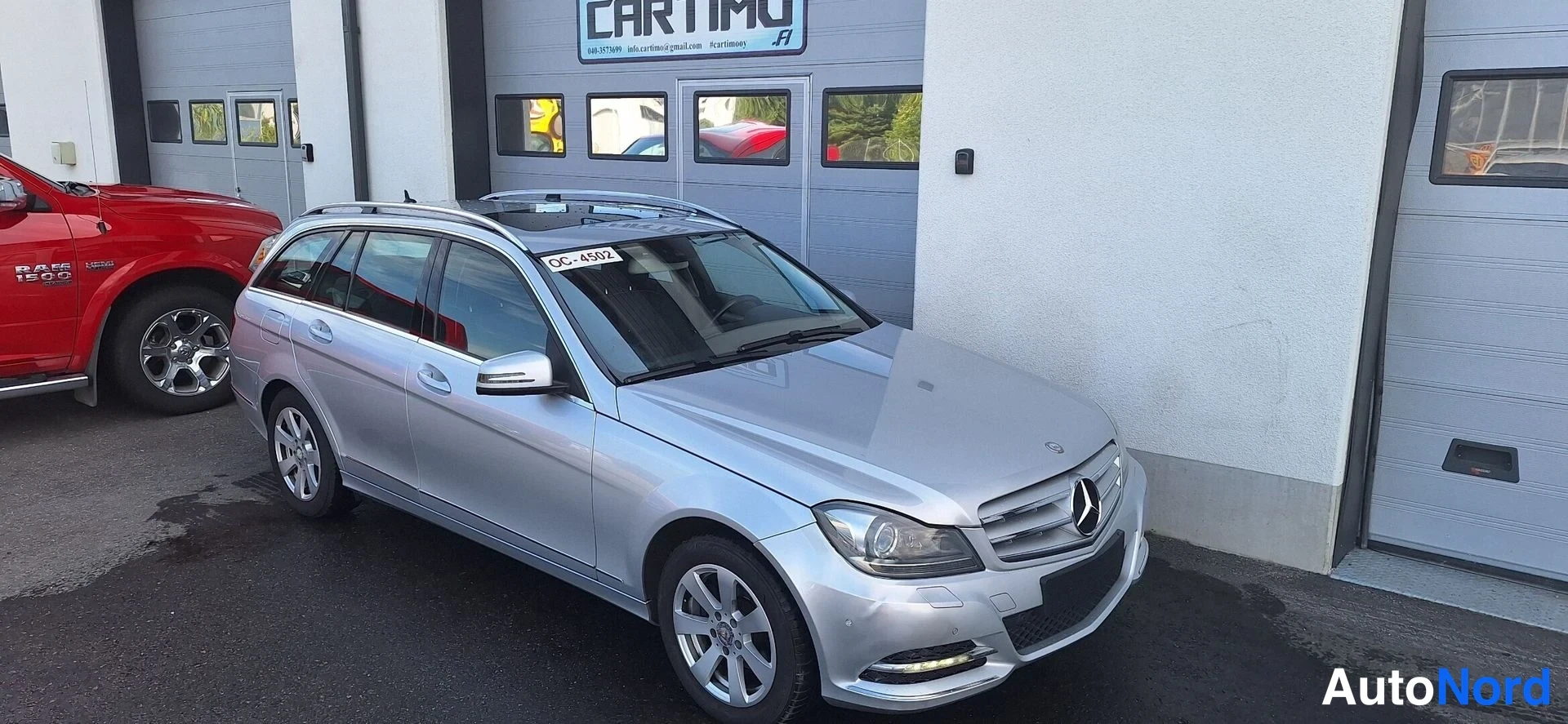 Etuviisto, nokka oikealle: Hopeanvärinen Mercedes-Benz C -farmari etu- ja sivupuolelta, konepelti ja etusäleikkö näkyvät oikealla.