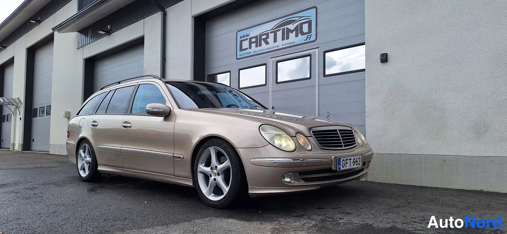 Etuviisto, nokka oikealle: Mercedes-Benzin keula oikealla, beige farmari hallin seinän vieressä.