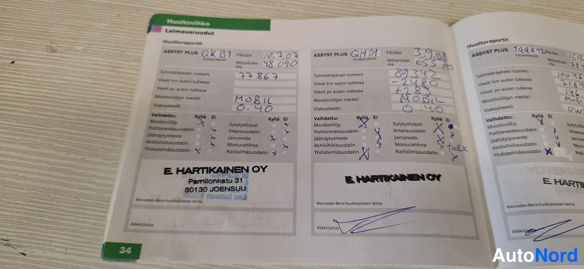 Asiakirja: Huoltovihko avattuna sivuille 34–35; käsinkirjoitetut Assyst Plus -huoltoraportit ja E. Hartikainen OY:n leimat ja allekirjoitukset.