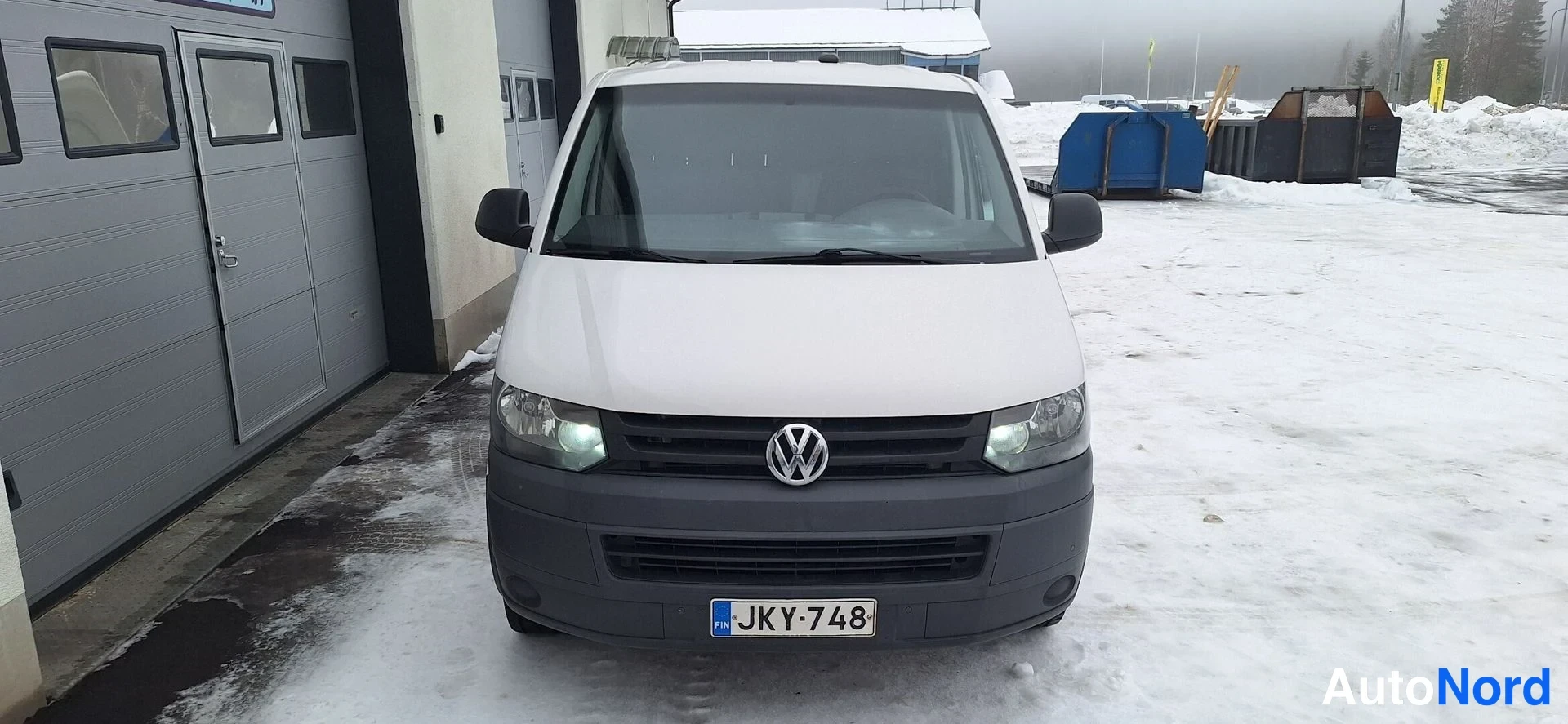 Edestä: Valkoinen pakettiauto edestä kuvattuna, tunnus.
