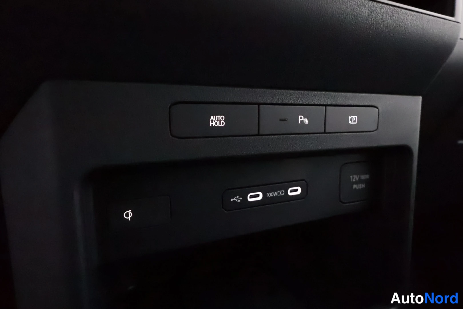 Muu: Sisäkuva: kojelaudan painikkeita (AUTO HOLD, kamerapainike), USB-C-portit merkintä 100W ja 12V-pistorasia PUSH-napeilla.