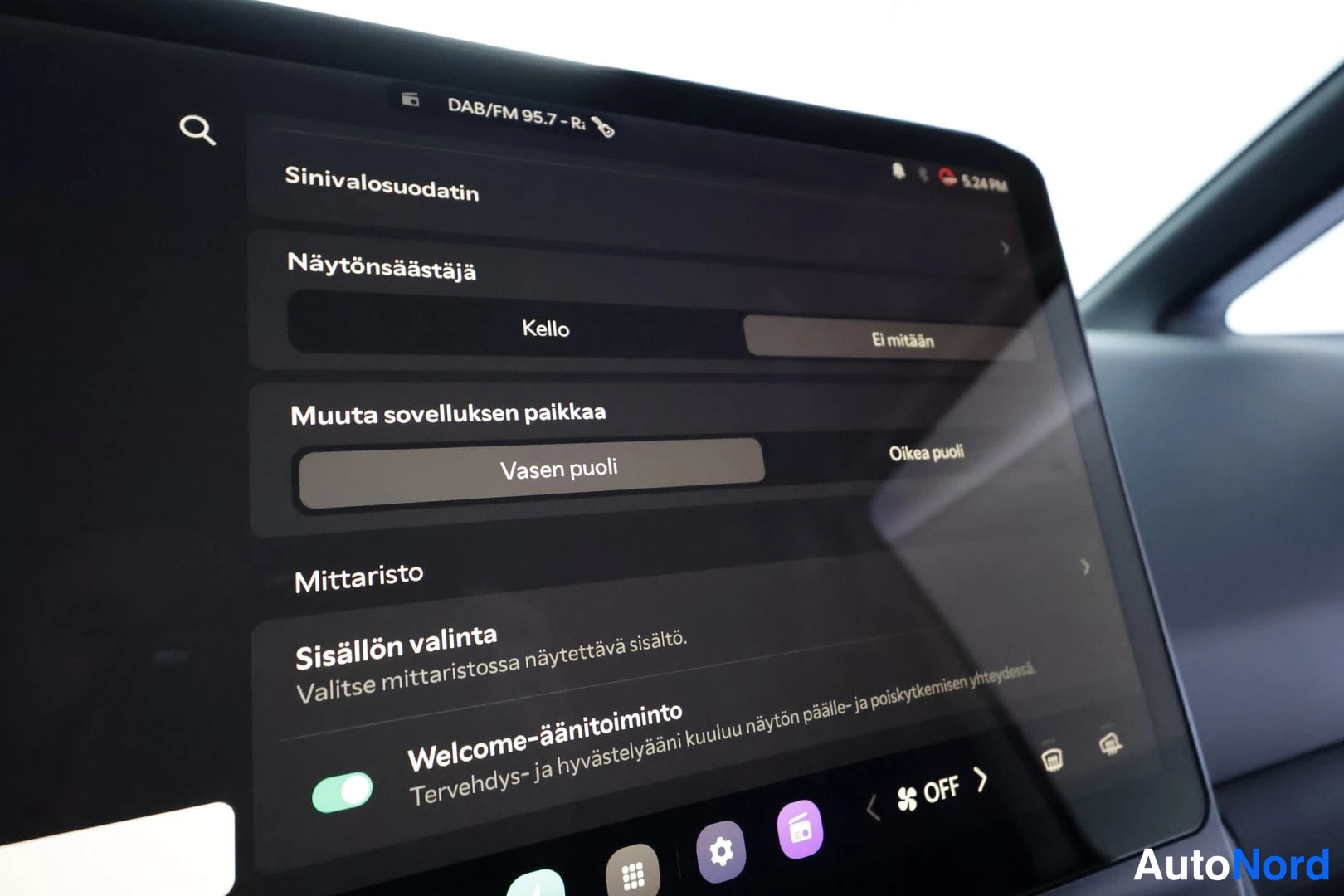 Yksityiskohta: Infotainment-näytön asetussivu, jossa valitaan näytönsäästäjäksi kello, sovelluksen paikka vasemmalle puolelle ja mittariston sisältösekä Welcome-ääntoiminto.
