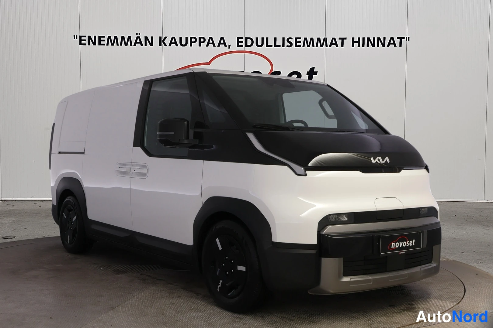 Etuviisto, nokka oikealle: Kia PV5 -pakettiauto etu kolmasosan kuvassa, nokka oikealla, valkoinen korimusta konekansi ja tummat pyörät.
