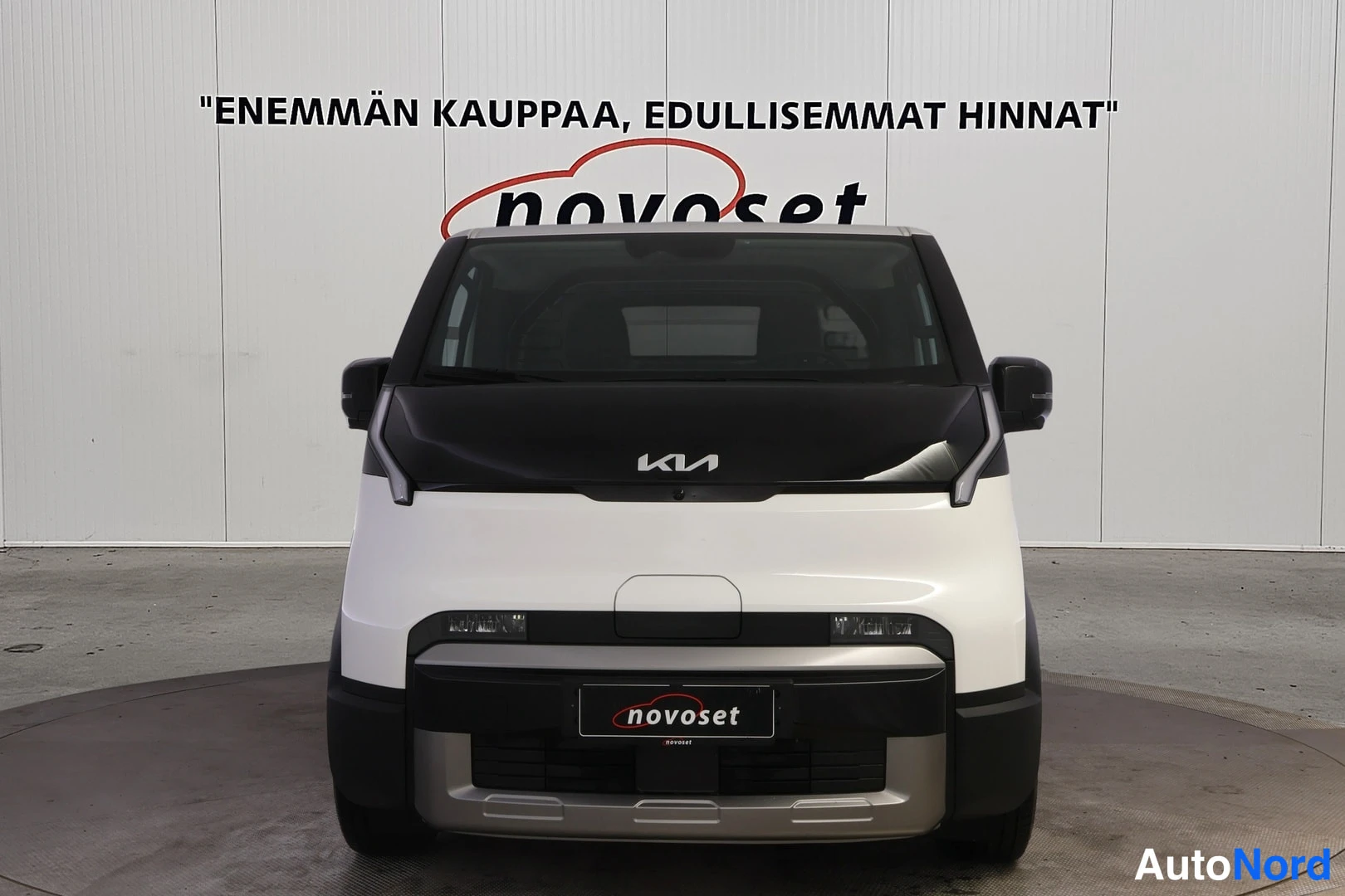 Edestä: Kia PV5 -pakettiauto suoraan edestä kuvattuna, valkoinen kori, musta konekansi ja KIA-merkki näkyvissä.