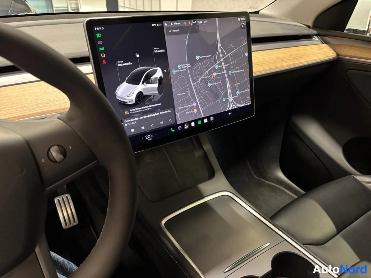 Muu: Kuljettajan näkökulma Tesla-automallin kosketusnäyttöön, jossa näkyy kartta ja ajoneuvon tilanäkymä.