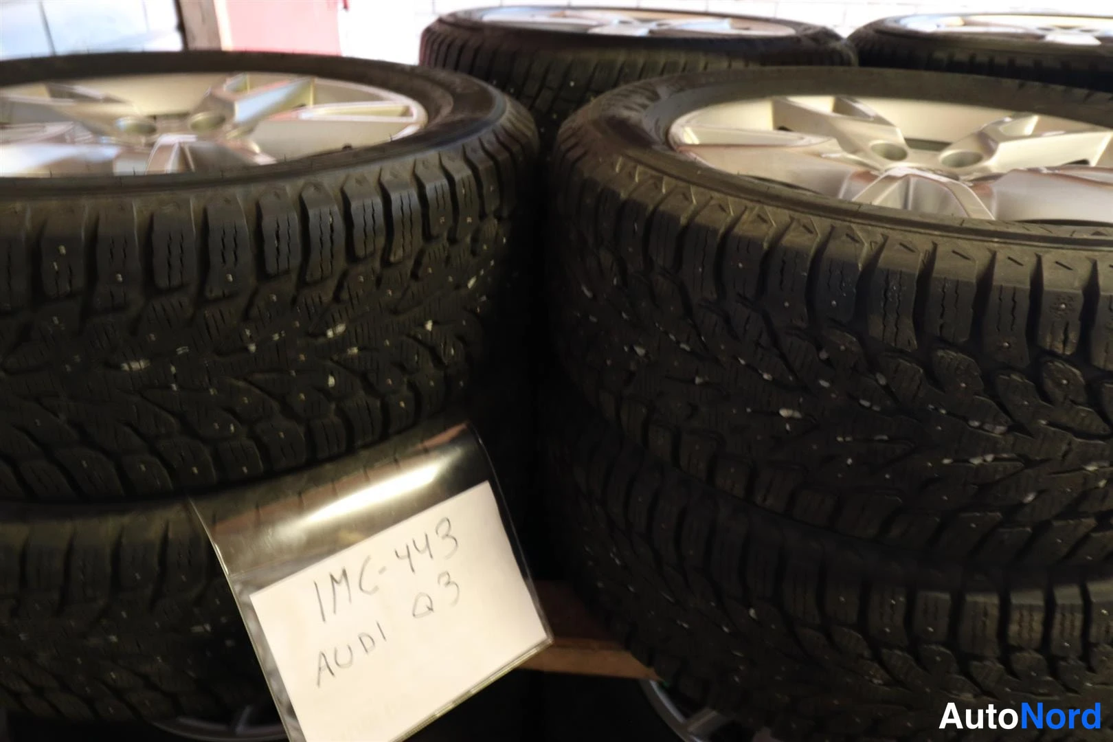 Muu: Auton takaa näkyy kasan kitkarenkaita kevytmetallivanteilla. Paikalla on käsin kirjoitettu laput, joihin on kirjoitettu ja AUDI Q3.