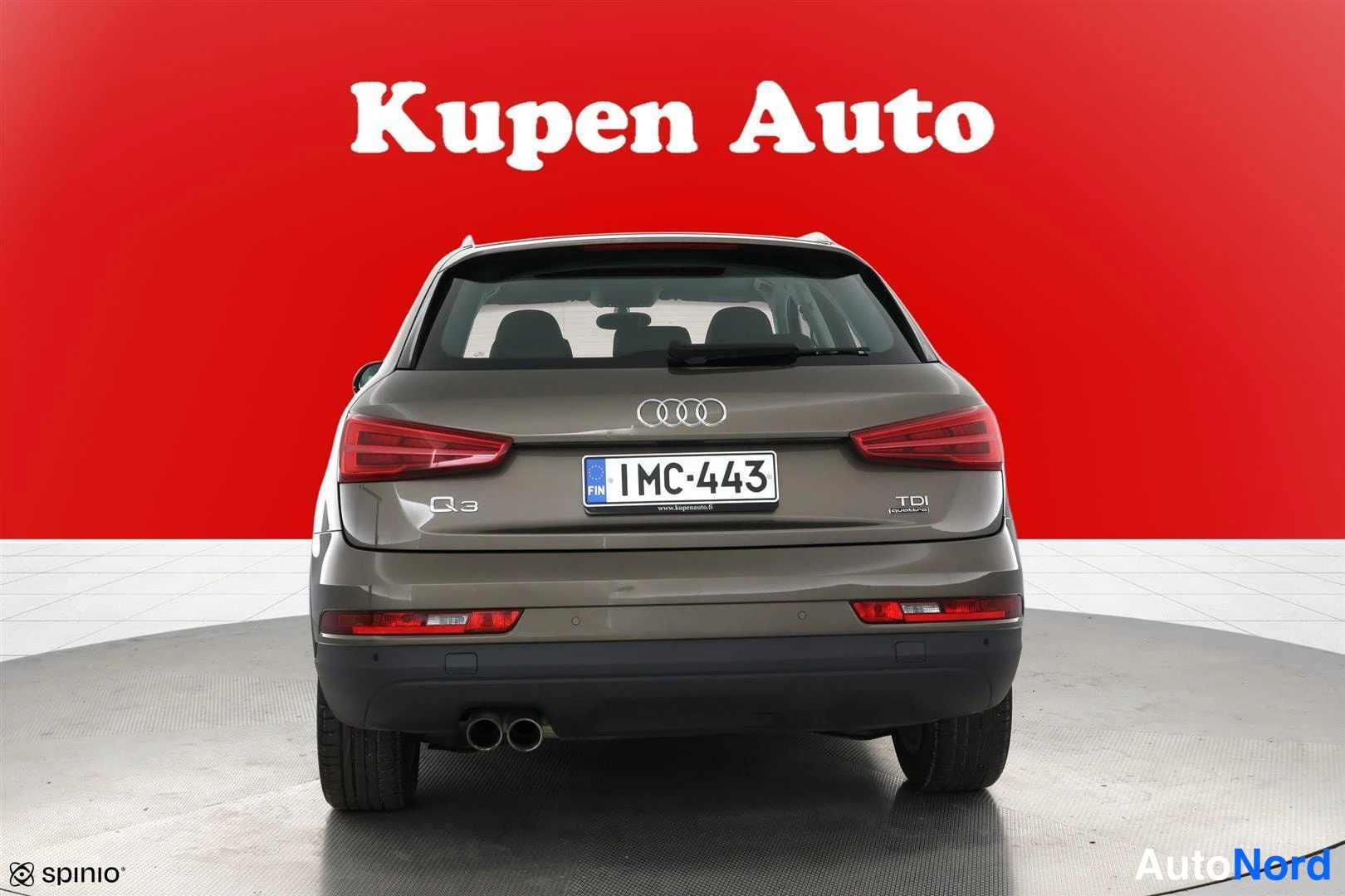 Takaa: Audi Q3:n takaapäin otettu kuva: ruskeanharmaa korirakenne, neljä kg-sarjaa, rekisterikilpi 1MC-443, TDI-tunnus ja kaksoispakoputki punaisella taustalla.
