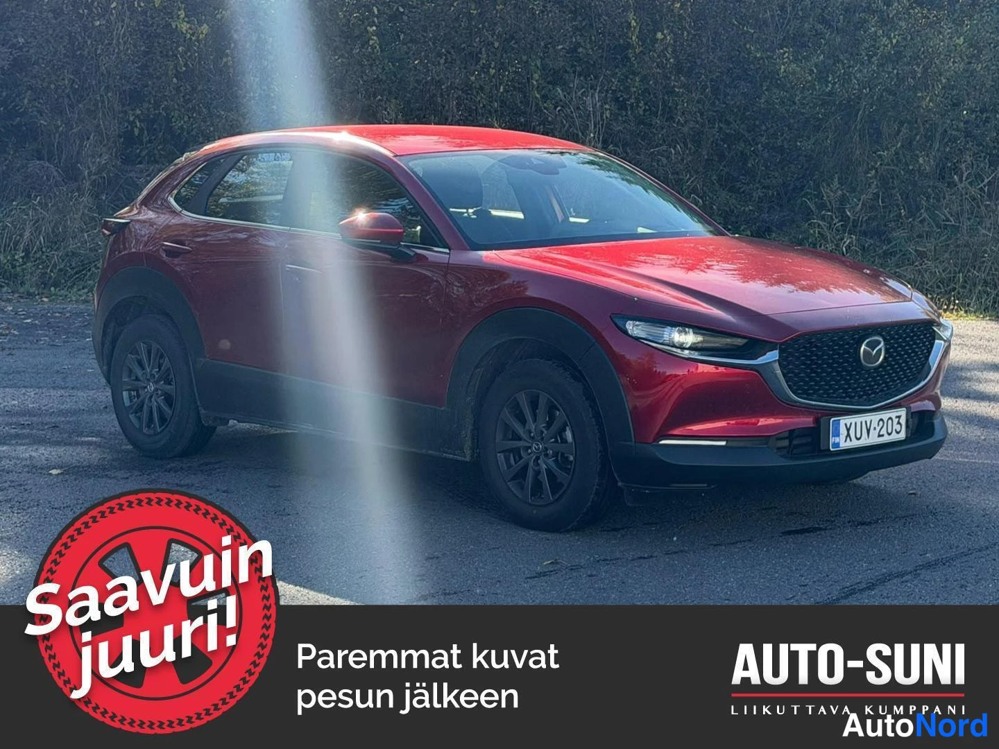 Etuviisto, nokka oikealle: Punainen Mazda CX-30 etukolmannesnäkymässä, keula kuvan oikeassa reunassa; etusäleikkö, ajovalot ja rekisterikilpi näkyvät.