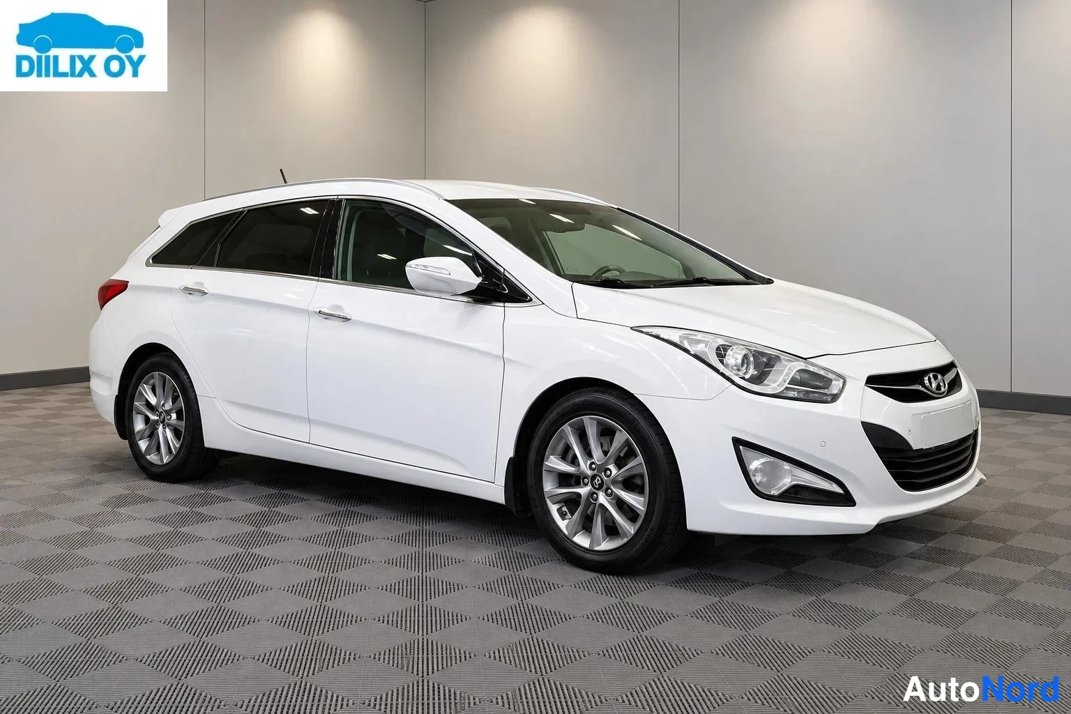 Etuviisto, nokka oikealle: Hyundai i40 -farmari etuviistosta oikealta valkoisena sisätiloissa.