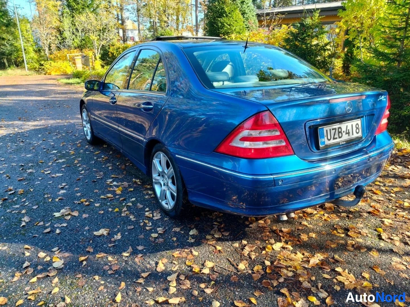 Takaviisto: Tummansininen Mercedes-Benz-sedan takanurkasta oikealta kuvattuna; takavalot, kannen kansi ja kylki näkyvät, rekisteritunnus.