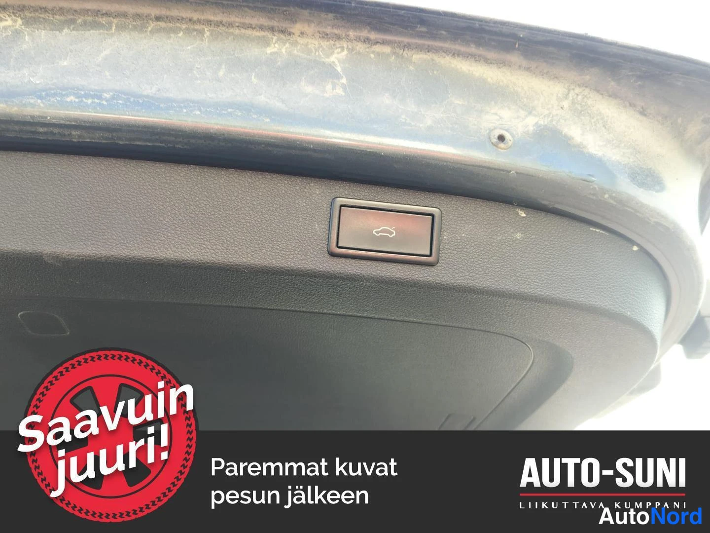 Muu: Yksityiskohtakuva takaluukun sisäpinnasta ja sähkötoimisen luukun avaamisnappulasta; maalipinnassa likaa ja kalkkijäämiä.