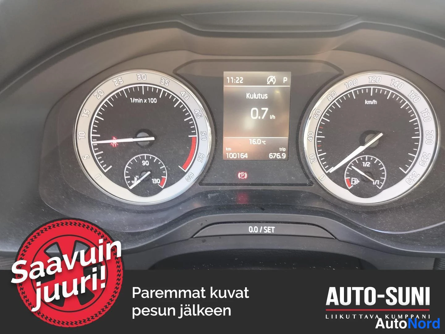 Muu: Auton kojelaudan mittaristön tarkempi kuva: nopeusmittari ja kierroslukijat sekä keskellä näyttö, jossa lukee 11:22, Kulutus 0.7 l/h, 16.0 °C, km 100164 ja trip