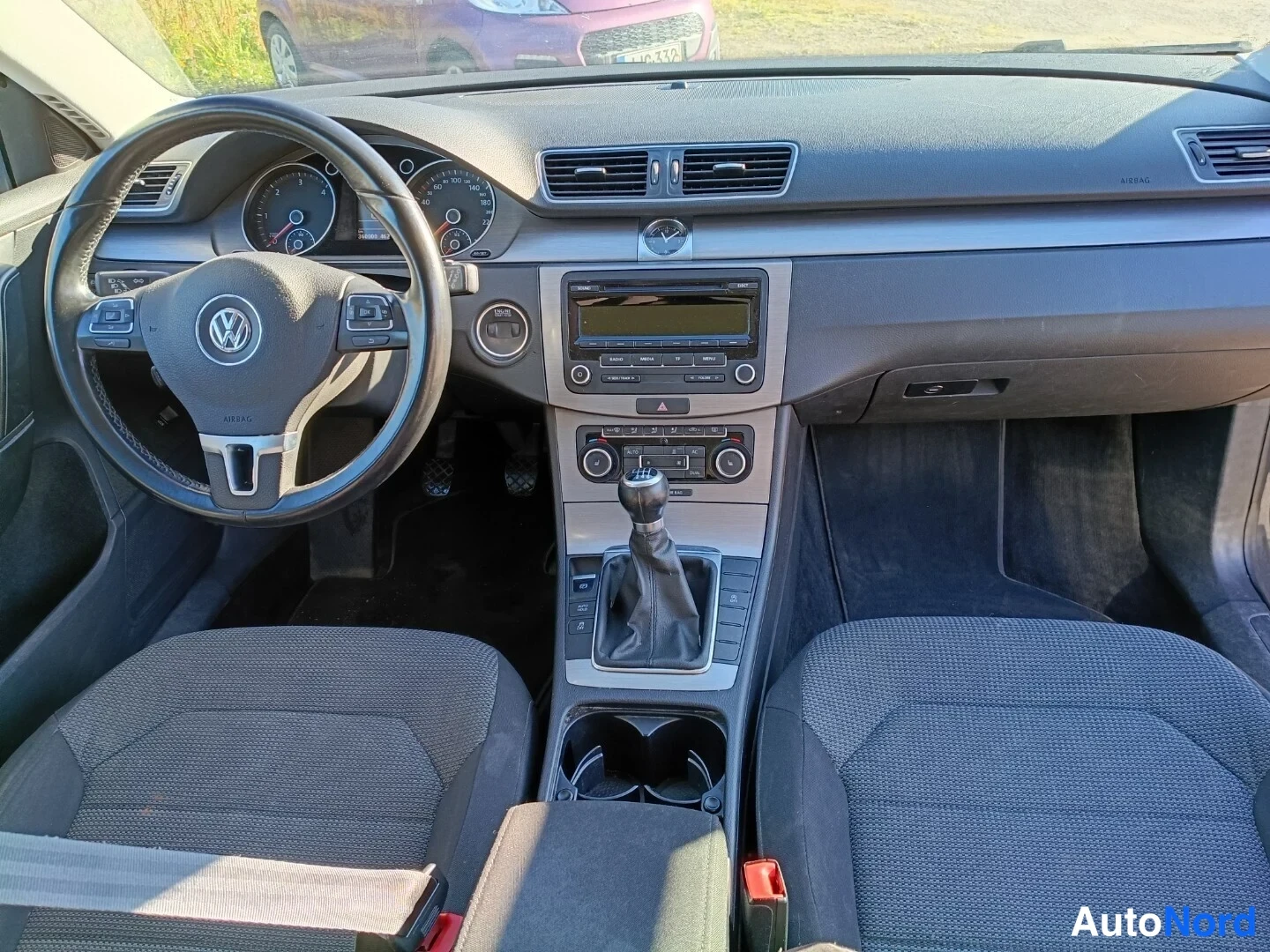 Muu: Volkswagenin auton sisätilat eteenpäin: ohjauspyörä, mittaristo, radiotaajuudella näkyvä radio ja manuaalivaihteisto.