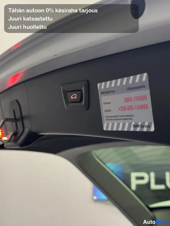 Muu: Sisäkuva takaluukun sisäpaneelista, jossa BMW Mobile Care -huoltotarra tekstillä Liikuunuspävelu ja puhelinnumero 0800-154000.