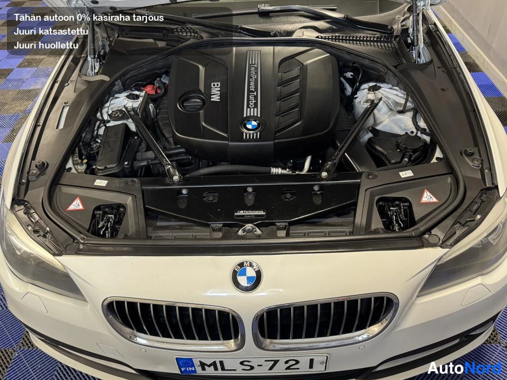 Edestä: Avoimet konepellin alla: BMW TwinPower Turbo -moottori, etusäleikkö ja rekisterikilpi näkyvät valkoisessa autossa.