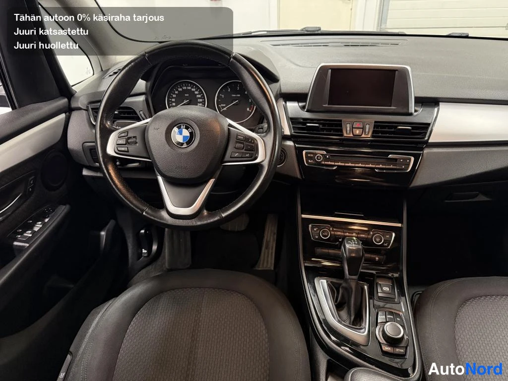 Yksityiskohta: Ohjaamo kuljettajan puolelta: BMW-ohjauspyörä, analogiset mittarit, infotainment-näyttö keskikonsolissa ja automaattivaihteen valitsin.