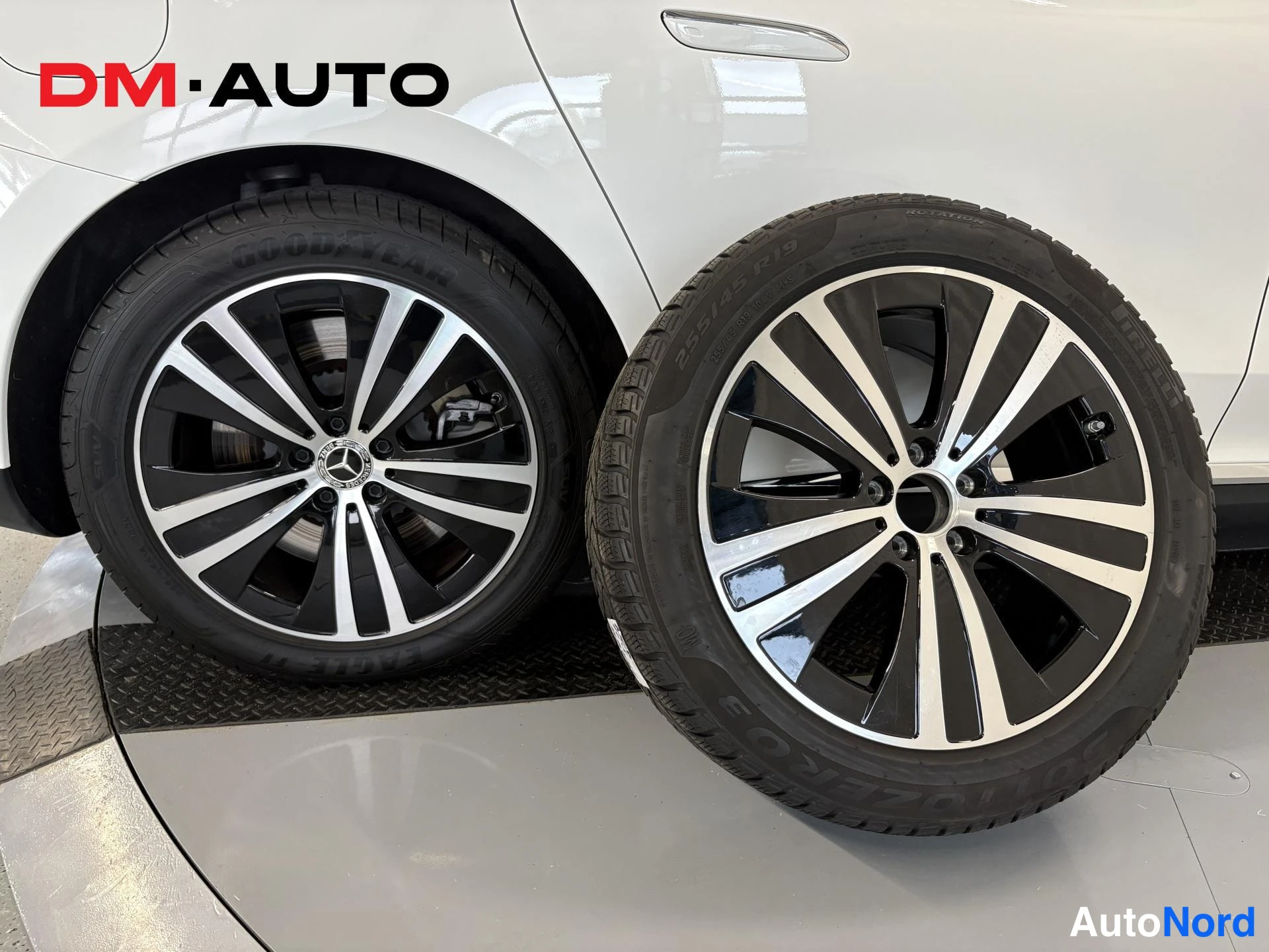 Yksityiskohta: Valkoisen auton takapyörä Goodyear-rengas ja vieressä erillinen Pirelli Sottozero -kavitusrengas 255/45 R19 vanteella.