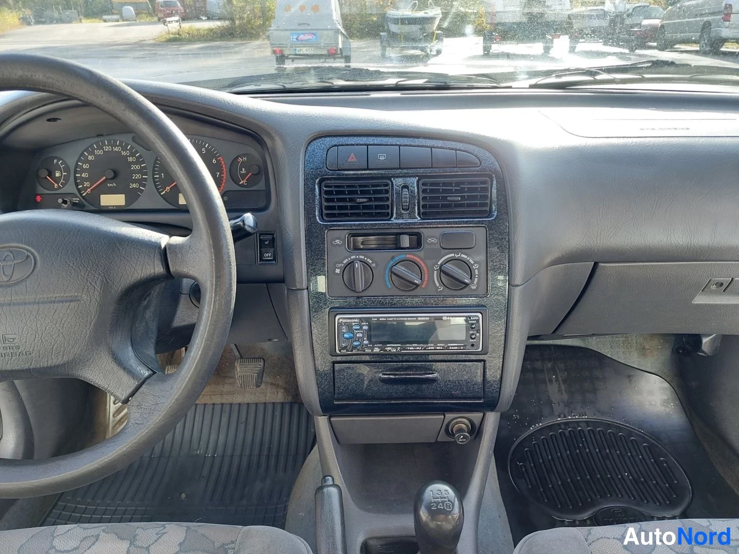 Muu: Lähikuva keskikonsolista: Toyota-ohjauspyörä, ilmastointisäätimet, Pioneer-radio ja manuaalivaihteiston vaihdekeppi.