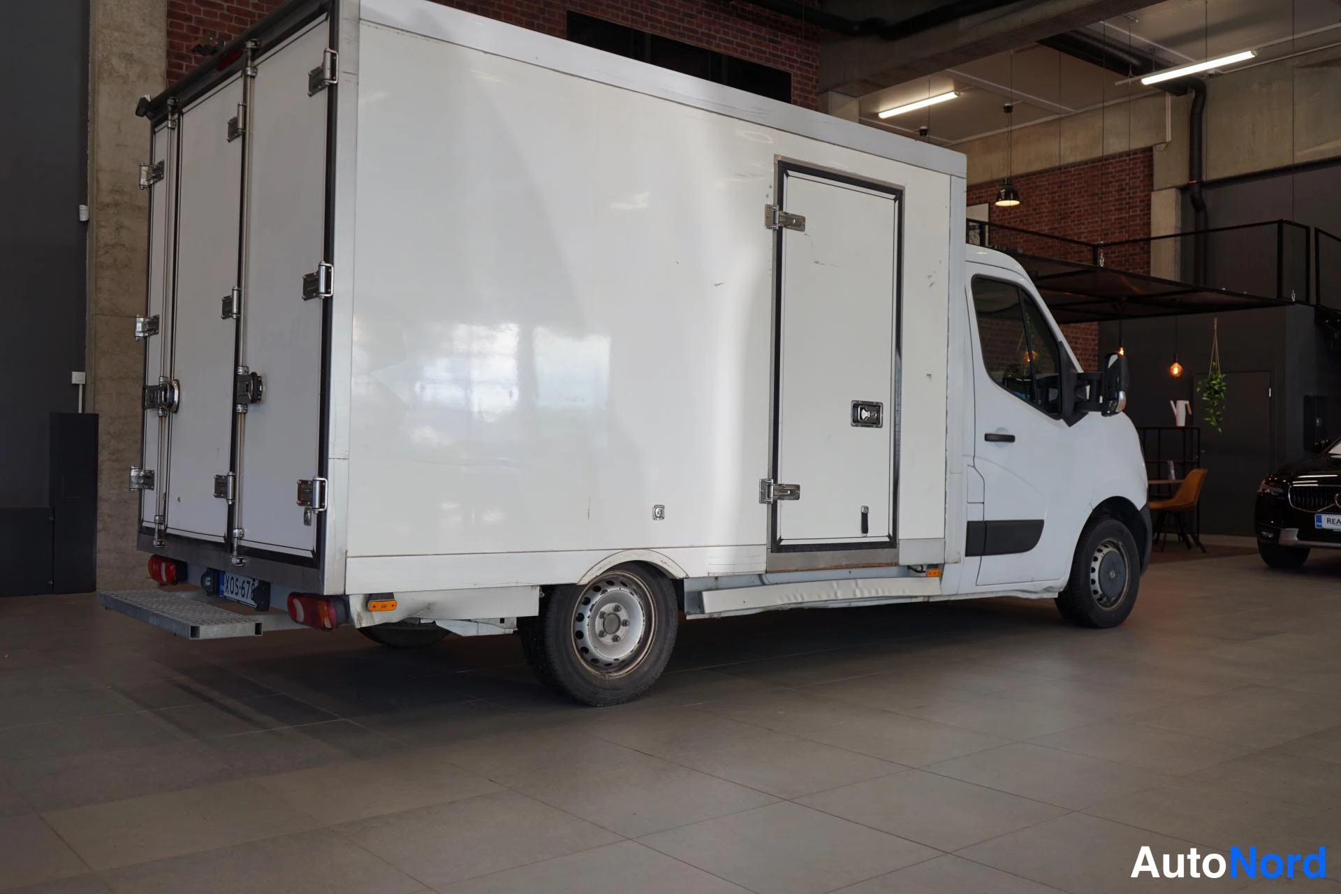 Takaviisto: Valkoinen Nissan NV400 -lavetuotantoauto takaa ja vasemmalta sivulta kuvattuna sisätiloissa.