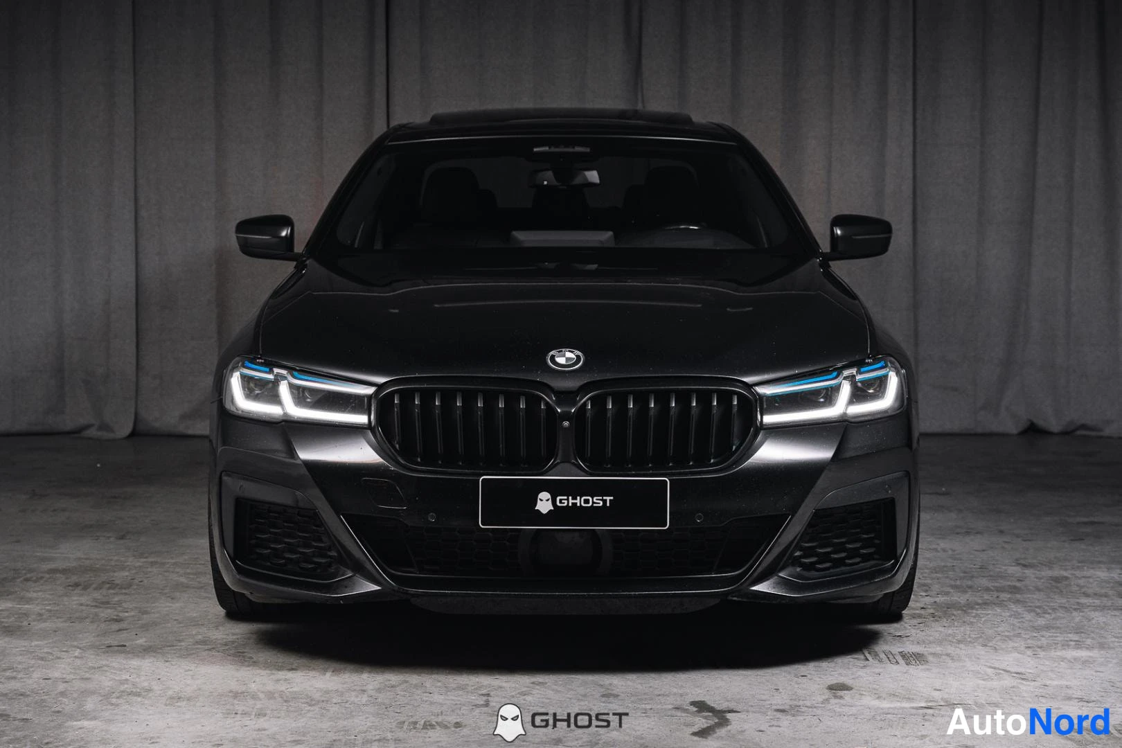 Edestä: Musta BMW-sedan suoraan edestäpäin, etusäleikön nimikilpi.