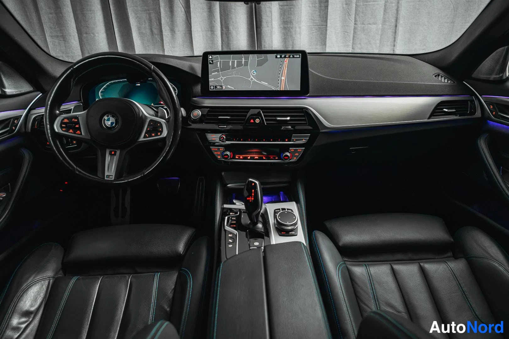 Muu: Auton etusumu kuvattuna keskeltä: BMW-ohjauspyörä, digitaalinen mittaristo, keskinäyttö kartalla, automaattivaihteen valitsin, iDrive-ohjain ja mustat etuistuim
